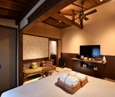 Spacious tatami-style room with low bed, wooden beams, shoji screens and seating at Muromachi Yutone Kyokoyado Kyoto