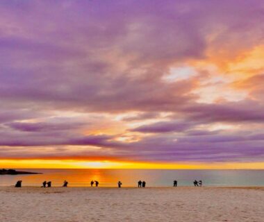 People on sandy beach at colorful sunset near Musashi ryokan, Wakayama coast