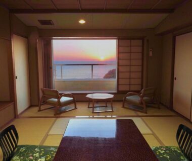 Sunset sea view through shoji from tatami room with low table and chairs at Musashi in Wakayama