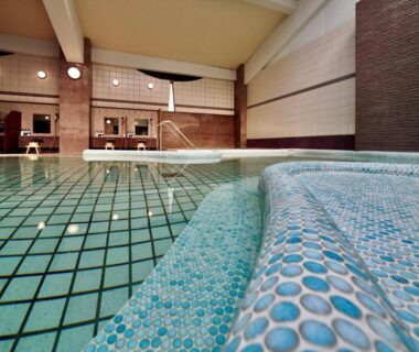 Mosaic tiled indoor bathing pool with steps and water jets at a ryokan in Wakayama