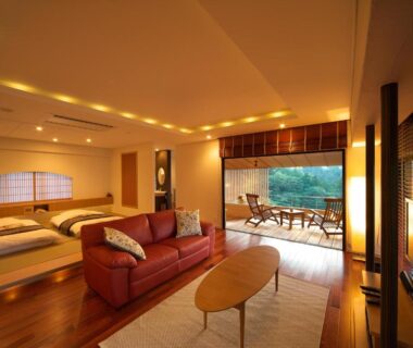Spacious room with sofa, low beds, shoji screen and open terrace overlooking greenery at Musashino Bekkan, Kanagawa