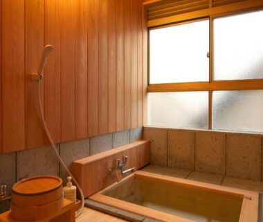 Wooden indoor soaking tub with shower, stool and frosted window at Musashino Bekkan in Kanagawa, Japan