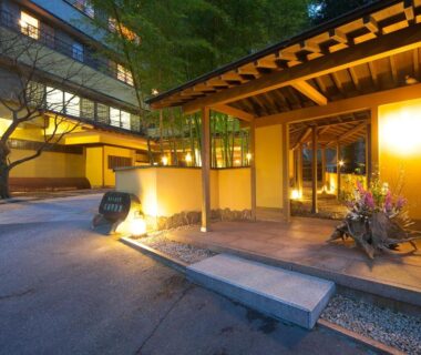 Lantern-lit wooden entrance with stone path and flower arrangement at Musashino Bekkan, Kanagawa