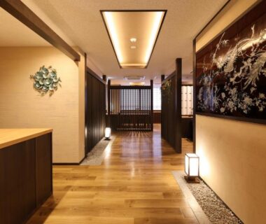 Interior hallway with wooden floors, shoji screens, lantern lighting and artwork at Mutsumikan ryokan in Gifu