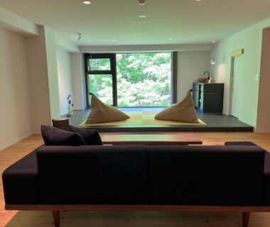 Minimal lounge with sofa, raised seating and garden view at Myojinkan Nagano