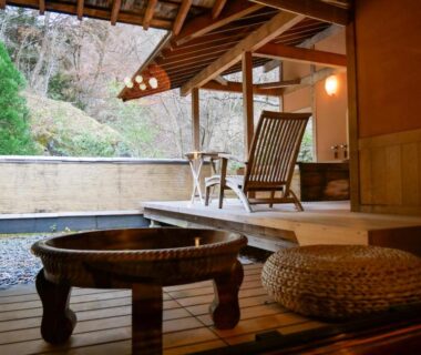 Outdoor wooden veranda with low wooden tubs, rocking chair and rattan cushion at Myojinkan in Nagano