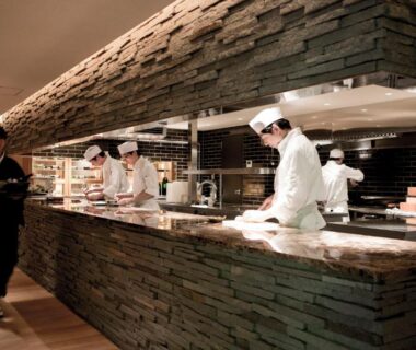Chefs preparing meals behind a stone counter in Myojinkan ryokan dining area, Nagano