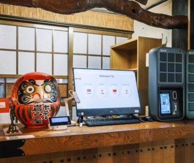 Wooden reception counter with daruma doll and digital check-in kiosk at Myoko Tsubame Iwatoya, Niigata