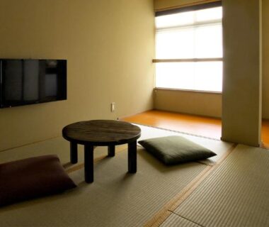 Tatami room with round low table, floor cushions, wall TV and freestanding bathtub at NAGOMI Kyoto Okazaki