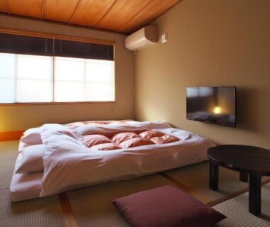 Low tatami room with futon bedding and round table at NAGOMI Okazaki, Kyoto Japan
