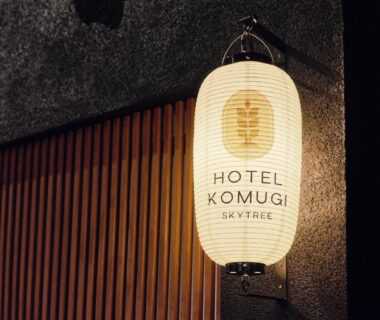 Illuminated paper lantern reading Hotel Komugi Skytree mounted by wooden slats on exterior in Tokyo