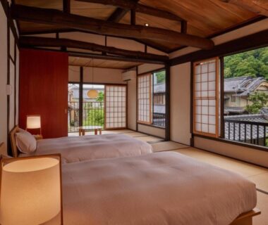 Twin low beds on tatami with shoji screens, wooden beams and balcony view at NIPPONIA HOTEL Takehara, Hiroshima