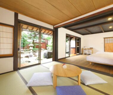 Tatami flooring, low table with cushions and Western bed overlooking a garden at NIPPONIA HOTEL Takehara, Hiroshima