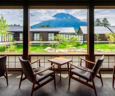 Four wooden chairs facing large window with mountain view at NISEKO Inn of Youtei Raku Suisan, Hokkaidō Japan