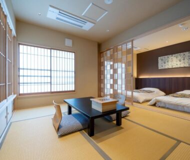 Tatami room with low table, floor cushions, futon beds and shoji screens at NISHIYAMA RYOKAN, Kyoto