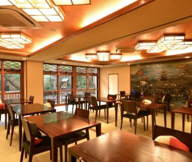 Dining room with wooden tables, chairs, decorative wall mural and lantern lighting at NISHIYAMA RYOKAN Kyoto