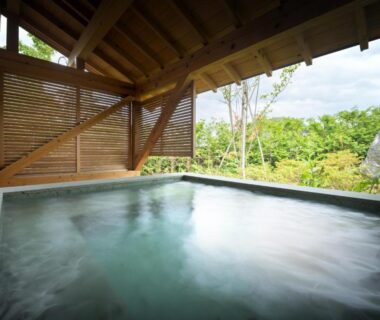 Sheltered wooden onsen bath with steaming water and garden views at Nagisatei Taroan in Iwate Tōhoku
