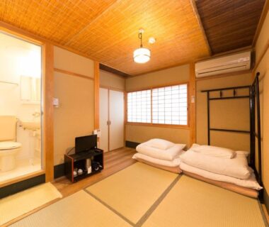 Traditional tatami room with futons, shoji screen, small TV and en suite bath at Nagomi-Ryokan Yuu in Kyoto