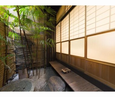 Enclosed bamboo courtyard with stone basin, wooden bench and shoji screens at Nagomi-Ryokan Yuu in Kyoto