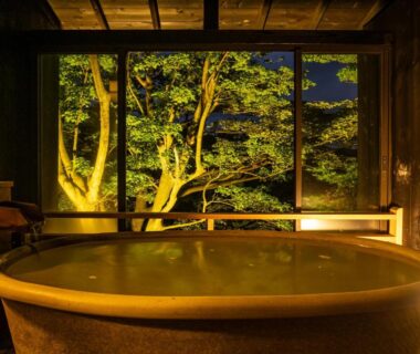 Round wooden indoor bath with illuminated garden view at Nagominoyado Hanagokoro, Kanagawa
