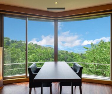 Dining table by large bay window with green hillside view at Nagominoyado Hanagokoro, Kanagawa