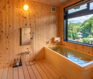 Indoor wooden bath with large window and mountain view at Nakamatsuya Ryokan in Nagano, Chūbu
