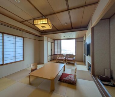 Traditional tatami room with low wooden table, shoji screens and window seating at Nakamatsuya Ryokan in Nagano