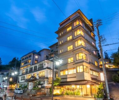 Lit multi-story building at dusk, Nakamatsuya Ryokan in Nagano