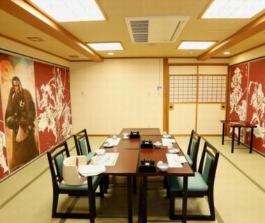 Tatami dining room with low tables, chairs, shoji screens and decorative wall murals at Nakamatsuya Ryokan in Nagano