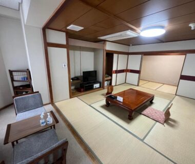 Tatami room interior with low table, cushions, shoji screens and seating at Nakamuraya Ryokan in Hokkaidō