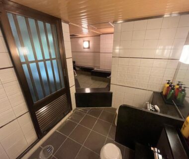 Tiled indoor bathing and washing area with stools and toiletries at Nakamuraya Ryokan in Hokkaidō, Japan