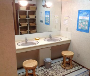 Double sink wash area with mirrors, wicker stools and cubby shelving at Nakayasu Ryokan in Ishikawa
