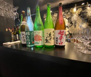 Sake bottles and glasses on a bar counter at Namari Onsen Kokoro No Toki Jusangatsu, Iwate