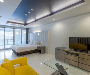 Spacious modern guest room with double bed, yellow armchair, TV and balcony at Namari Onsen Kokoro No Toki Jusangatsu Iwate