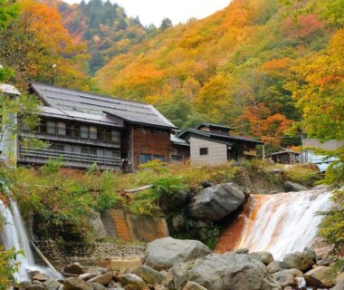 Riverside wooden buildings and small falls at Namegawaonsen Fukushimaya in Yamagata mountains