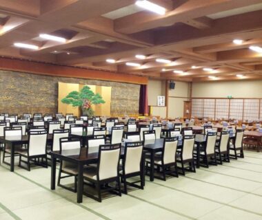 Large tatami-covered banquet room with rows of tables and chairs, shoji screens and decorative folding screen at Nangoku Hotel Chiba