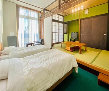 Room with twin Western beds, tatami seating area, shoji screens and balcony light at Nangoku Hotel in Chiba