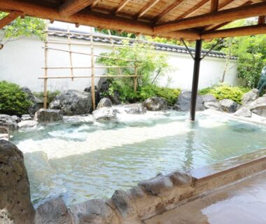 Covered stone onsen bath with wooden roof and garden at Nanpeidai Onsen Hotel, Tochigi, Kantō