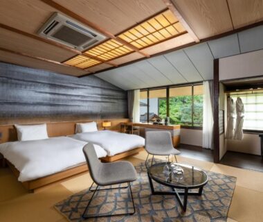 Tatami-floored room with twin beds, low glass table, seating and garden view at Nanzenji sando KIKUSUI in Kyoto