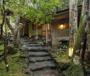 Moss-covered stone steps leading to the ryokan entrance amid trees and lanterns in Nara, Kansai