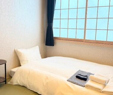 Single futon on tatami with shoji window and folded linens at Nara Ryokan in Nara