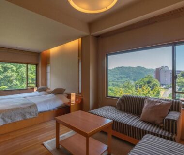Two single beds, wooden floor, sofa and large windows with green mountain view at Narashino no sato Gyokusui Shizuoka