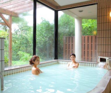 Two guests bathing in tiled indoor onsen with garden-facing windows at Nasu Hoshi no Akari, Tochigi