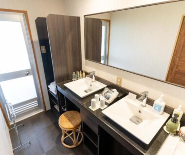 Twin washbasins and large mirror with wooden stool and toiletries in ryokan bathroom at Nasu Onsen Sanraku Tochigi