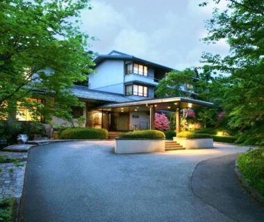 Entrance of Nasu Onsen Sanraku ryokan with lit driveway and surrounding trees in Tochigi, Kantō, Japan