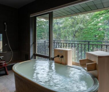 Indoor wooden onsen bath with shower and balcony overlooking forest at Nasu-Onsen Shinshun no Kago Hewitt Resort Tochigi