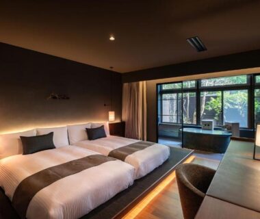 Twin bedroom with two beds, desk, and a wooden soaking tub by window overlooking greenery at Nasu-Onsen Hewitt Resort, Tochigi