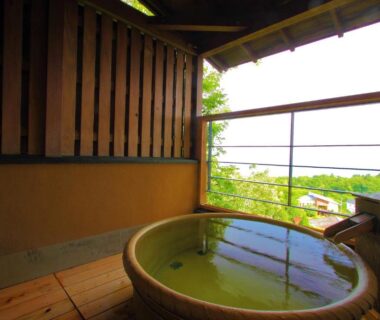 Round wooden outdoor bath on balcony overlooking greenery at Nasubi no Hana, Shizuoka