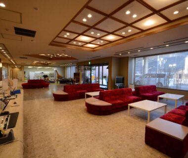 Ryokan lounge with red sofas, large windows and polished floor at Nasushiobara Ichimantei in Tochigi