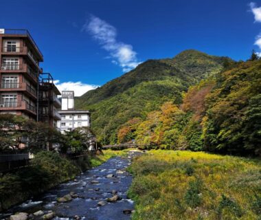 Riverside ryokan building beside mountain stream with wooded hills in Tochigi, Kantō, Japan